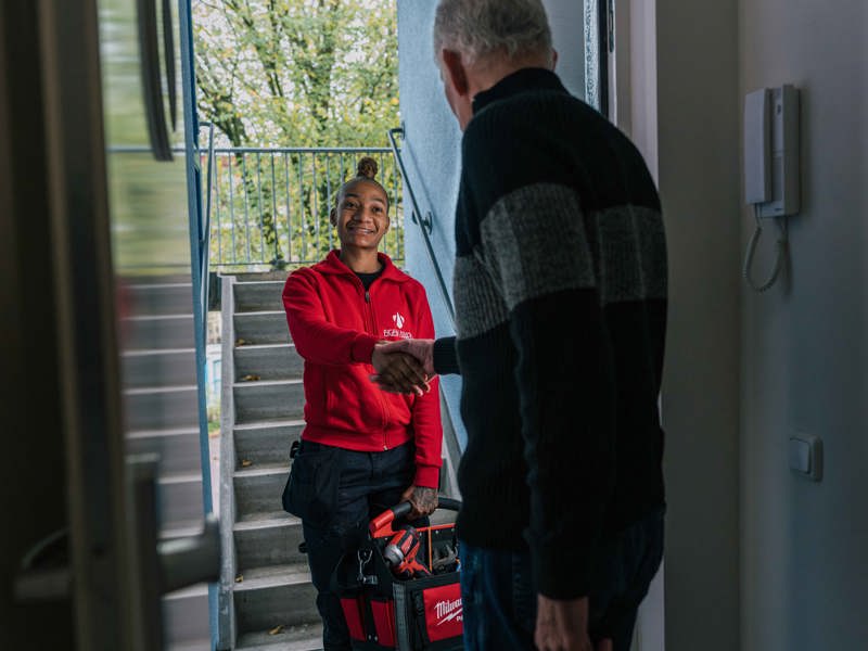 Vrouwelijke monteur staat voor de deur en lacht